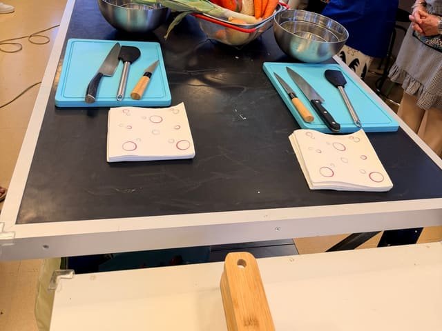 Mesa de trabajo preparada con hortalizas frescas y utensilios antes de empezar el taller