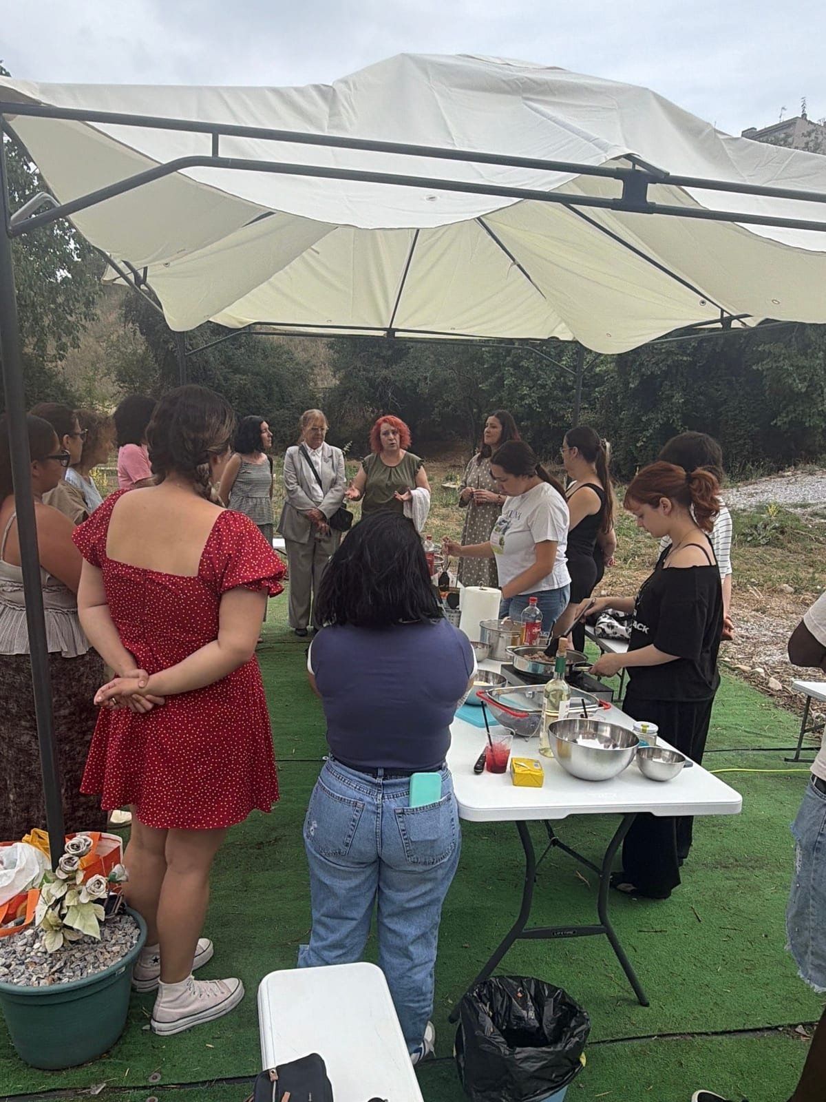 Grupo participando en un taller de cocina al aire libre bajo una carpa